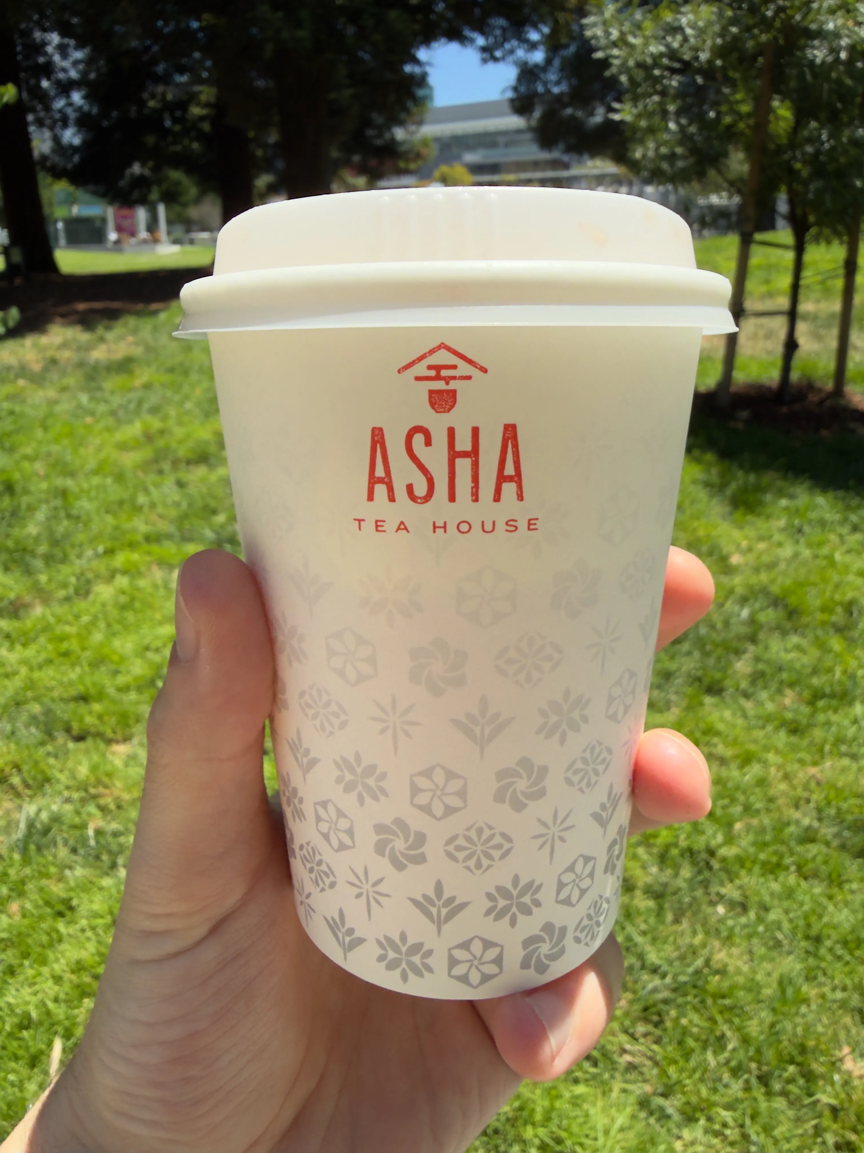 Front side of a tea cup from Asha Tea House, showing their label and stylized tea leaves