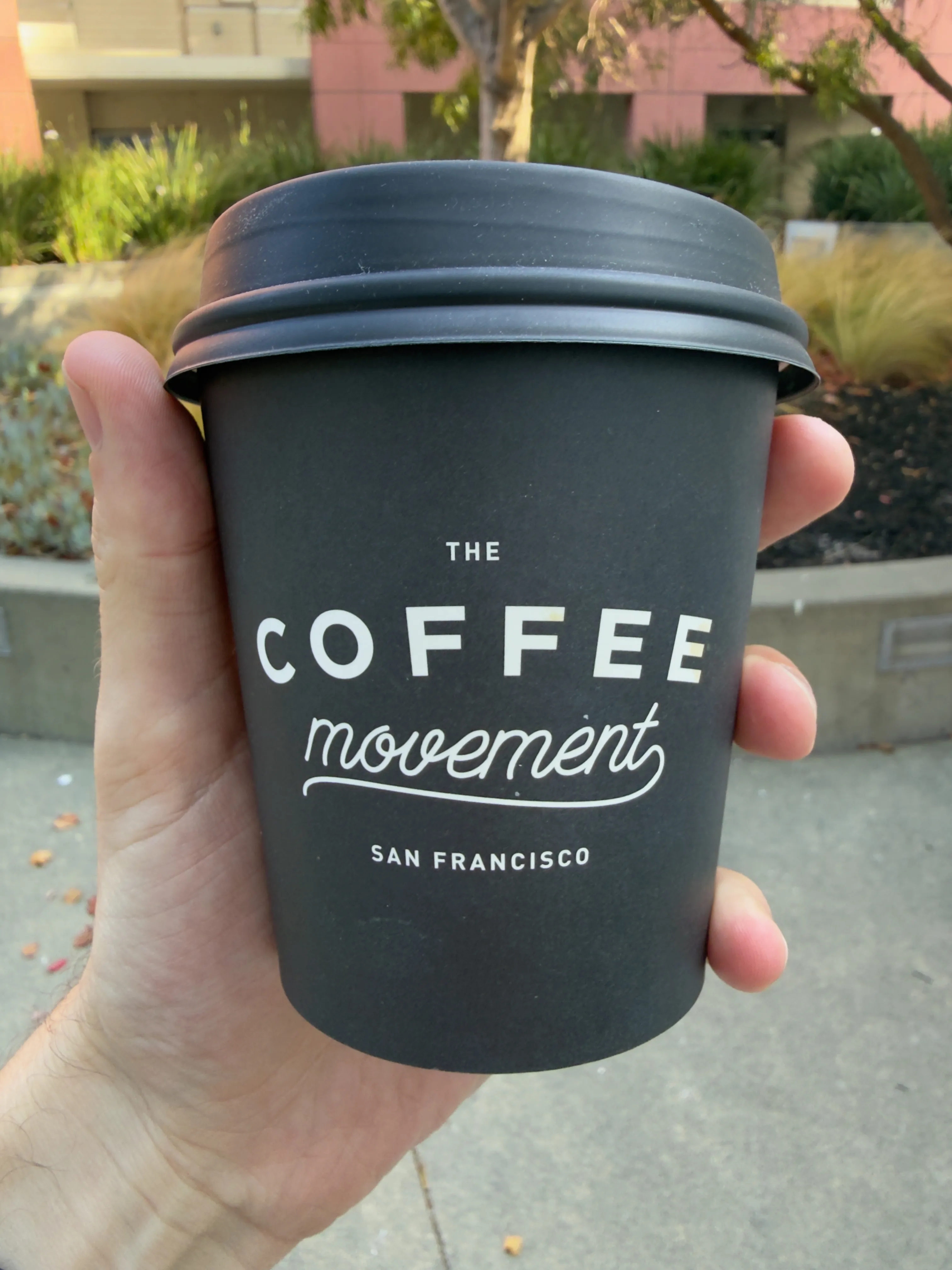 Front side of a coffee cup from Coffee Movement, showing their label Front side of a coffee cup from Coffee Movement, showing their label