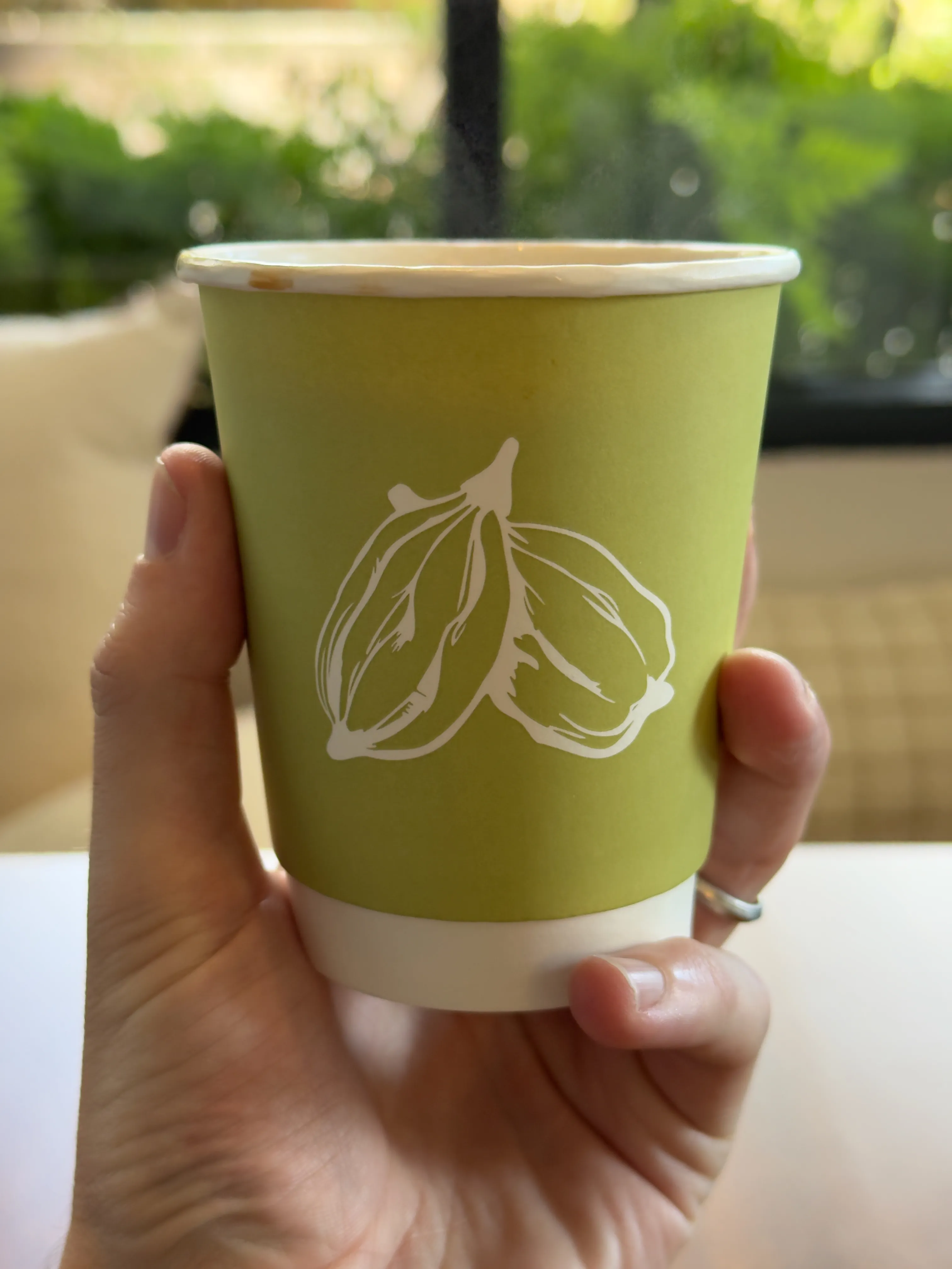Front side of a coffee cup from elaichi co, featuring a cardamom pod (?)