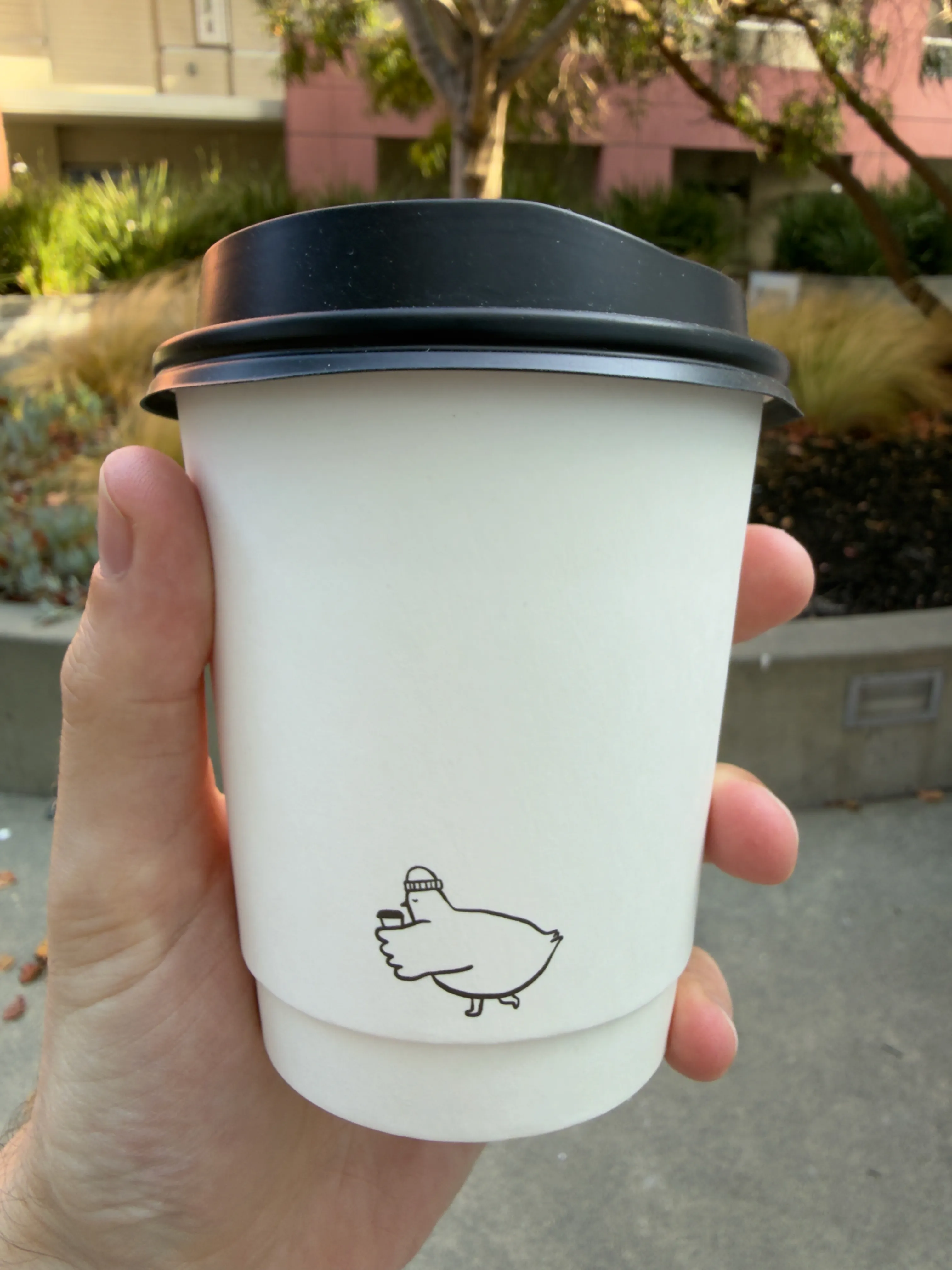 Back side of a coffee cup from Paper Son, showing their label and their stylized bear character Back side of a coffee cup from Paper Son, showing their label and their stylized bear character