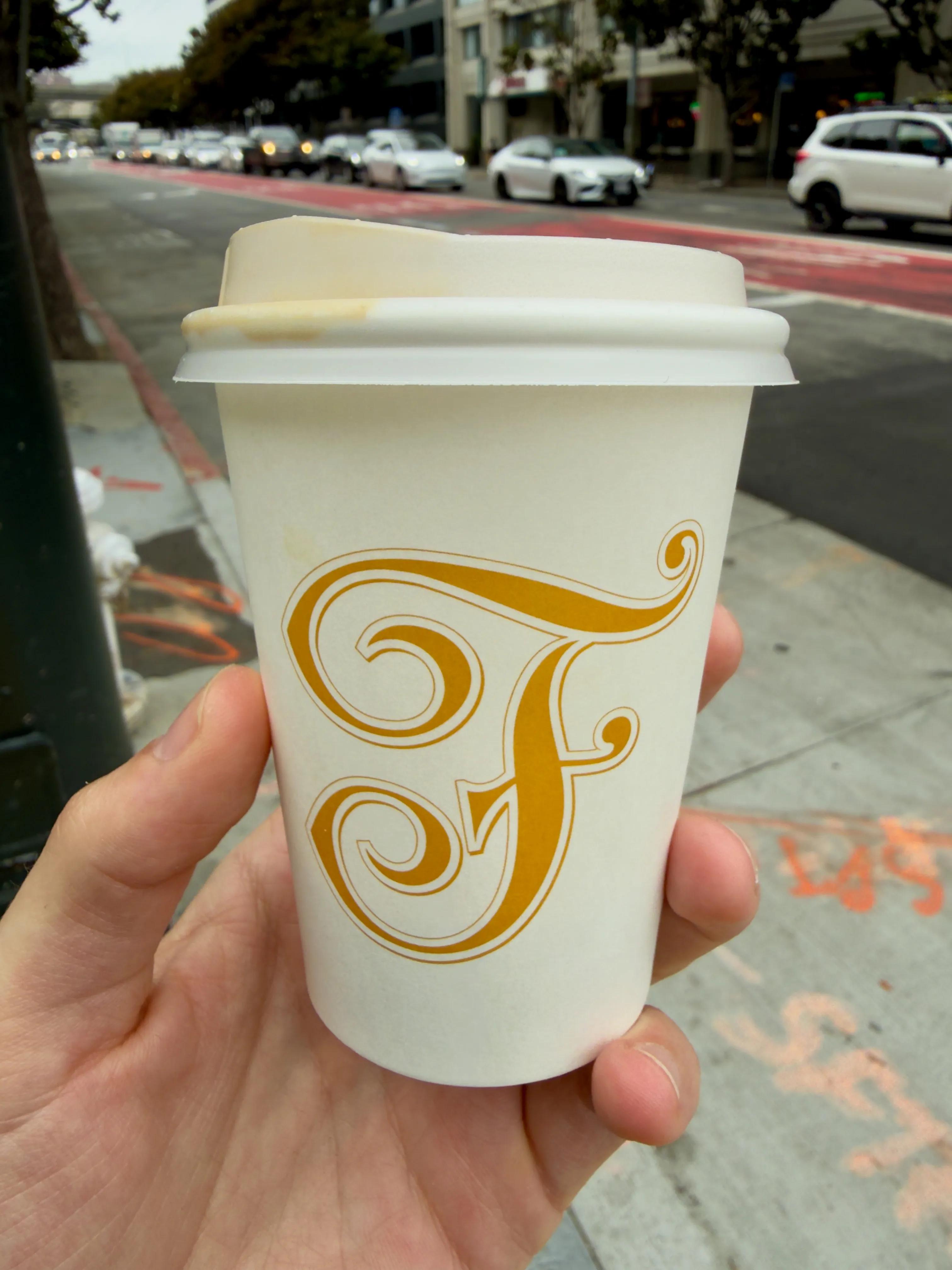 Front side of a coffee cup from Saint Frank Coffee, showing their stylized-F label Front side of a coffee cup from Saint Frank Coffee, showing their stylized-F label